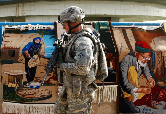 Image: A U.S. soldier walks past Iraqi carpets for sale at the Jadriya Lake park in Baghdad