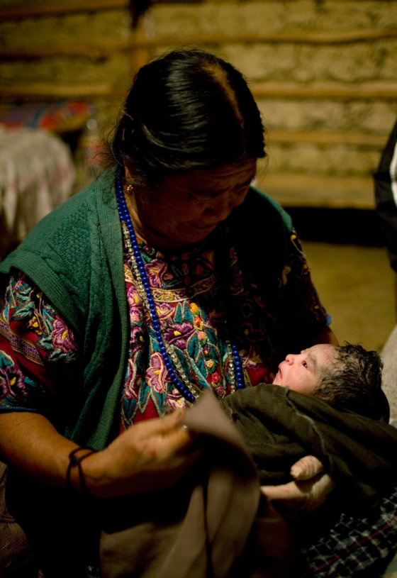 Image: Rural midwife Francisca Raquec, left, holds Sara Raquec's newborn son in El Llano