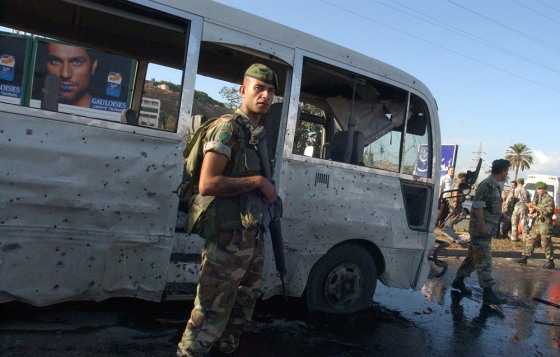 Image: Lebanese soldiers stand guard near a damaged bus
