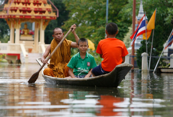Image: A monk paddles a boat through flood waters at a temple in Thailand's Lopburi province