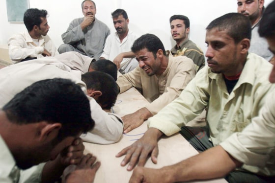 Image: Iraqi men mourn over the coffin of a relative in a mosque, in Karbala