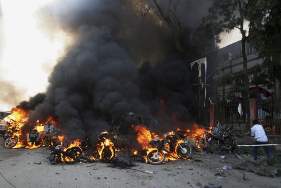 Image: A man tries to extinguish fire near a blast site in Gauhati, India