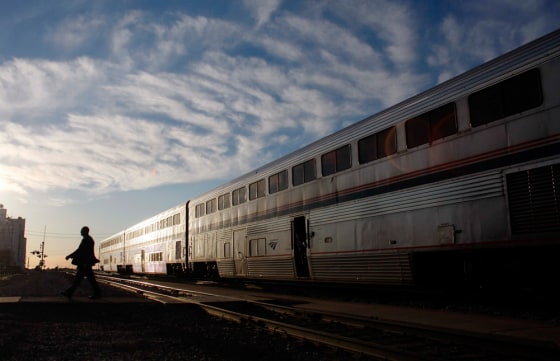 Image: An Amtrak train attendant walks across the tracks
