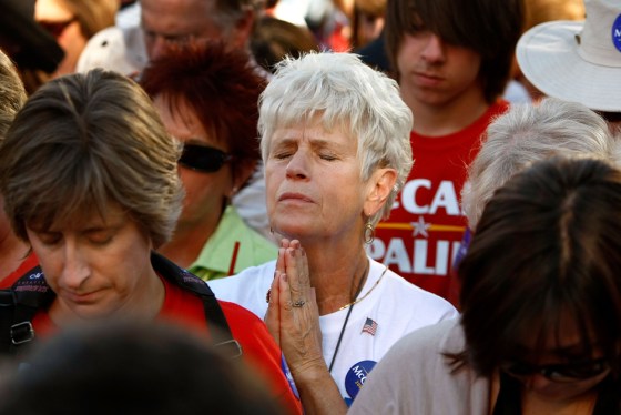 Image: A woman prays before the start of a rally with Republican presidential nominee Sen. John McCain
