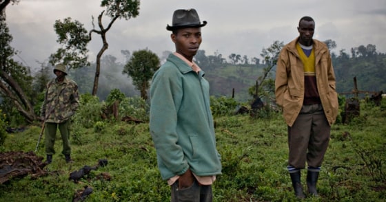 A Kenyan park ranger stands near residents who live on disputed land at the Mau forest