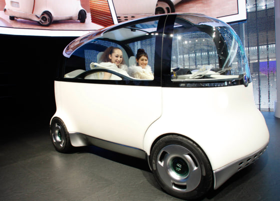 Models pose with Honda Motor Co's new Puyo concept car at a photo opportunity during the 40th Tokyo Motor Show in Chiba