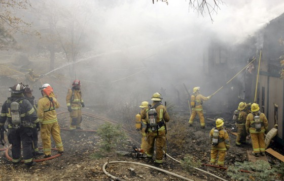 Firefighters from various California towns fight a house fire ignited by the Slide wildfire in Arrowbear, Calif., on Saturday.