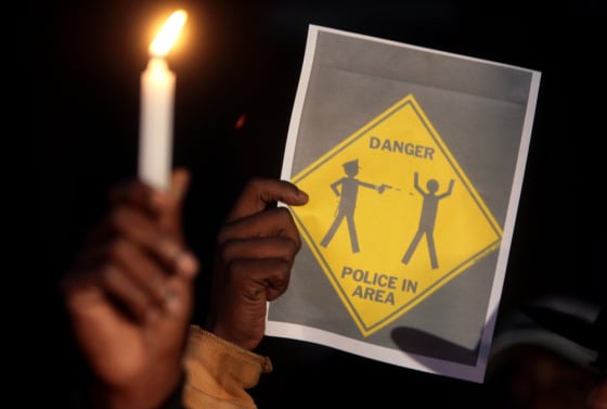 Image: A warning sign is held up during a candlelight vigil