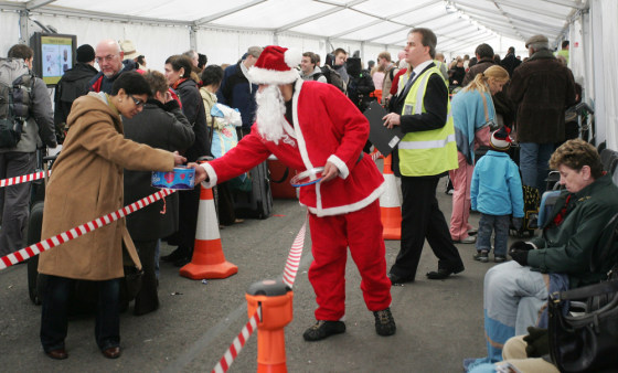 Image: airport staff dressed in a Santa outfit hands out sweets to passengers waiting in a tent