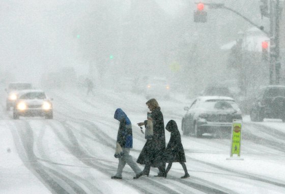 Pedestrians brave the blowing snow as they cross the main street of Chagrin Falls, Ohio on Sunday. 