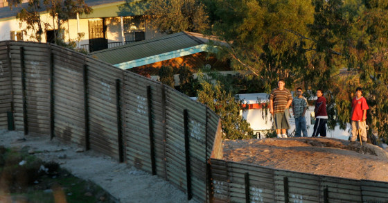 Image: A group of boys gather on the Tijuana side of the primary fence separating the United States and Mexico in a neighborhood known as Colonia Libertad.