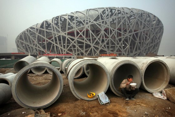 A Chinese worker eats lunch next to the iconic National Stadium — nicknamed the "Bird Nest" — under construction for the 2008 Beijing Olympic Games, in this photo from Nov. 12, 2007.