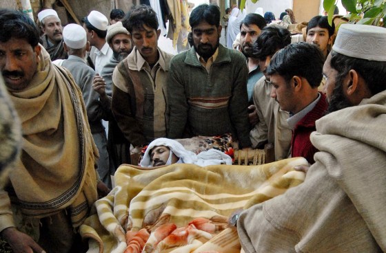Pakistani villagers carry a man injured in a suicide attack in Sherpao on Friday.