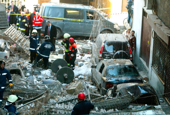 Image: Firemen stand amid rubble after an explosion in a factory