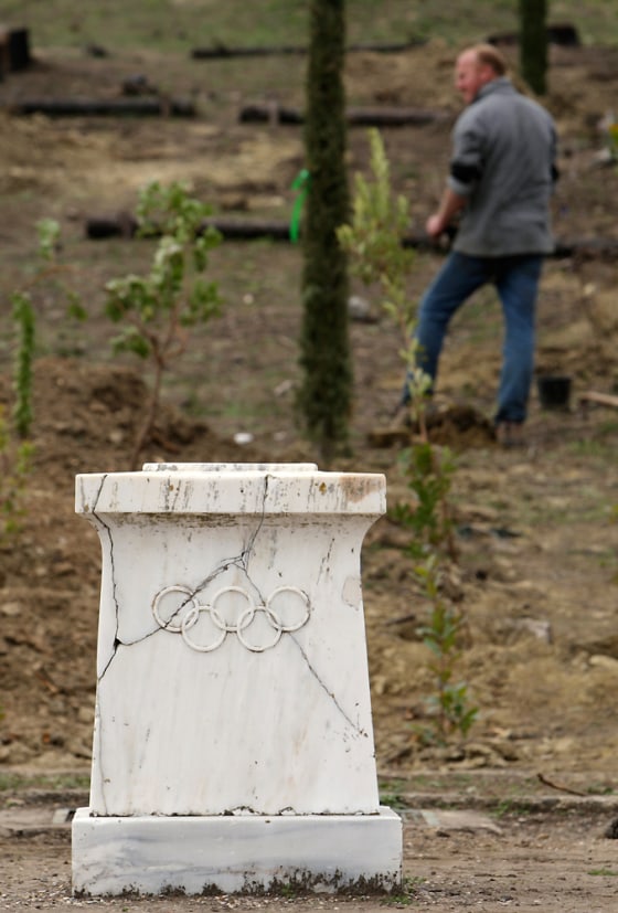 Image: A worker plants cypress trees behind an altar at the Pierre de Coubertin monument in ancient Olympia
