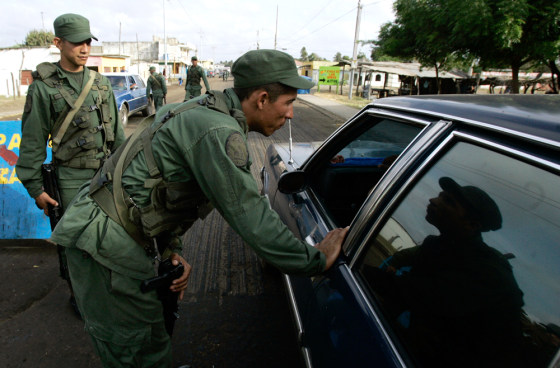 image: Venezuelan National Guard soldiers inspect a car.