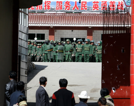Image: Tibetans look at the Chinese riot police in Xiahe, Gansu Province, China