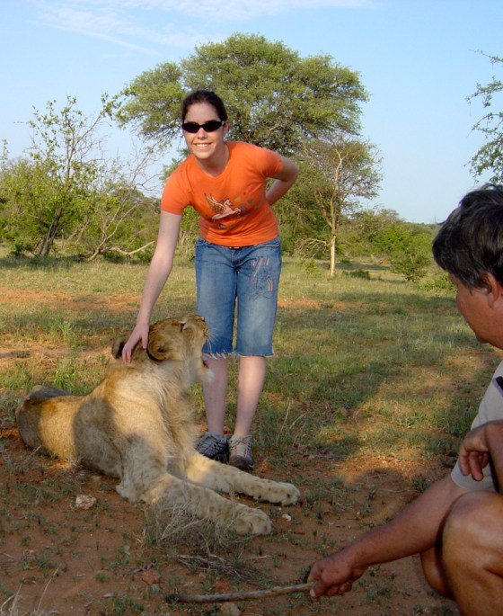 Image: Ashley Kahn standing beside a 6 month-old male lion cub