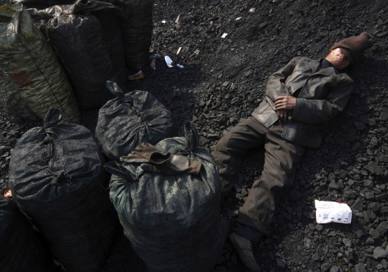 Image: A labourer takes a nap after searching for usable coal at a cinder dump site in Changzhi, China