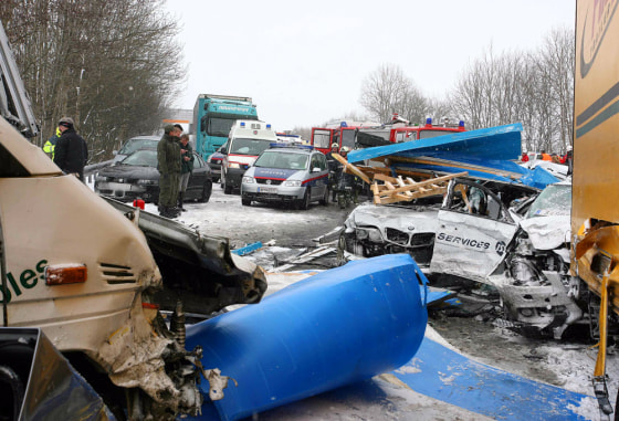 Image: Rescue personnel are seen next to the wreckage of vehicles.