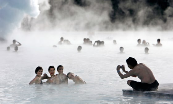 Image: Bathers pose for a photo as they swim in the geothermal hot springs at Iceland's Blue Lagoon