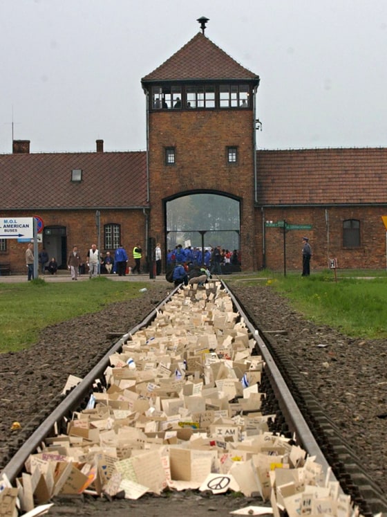 Image: People place memory plaques on rails in Birkenau