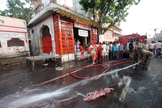 Image: An Indian firefighter washes off one of the blast sites in Jaipur, India