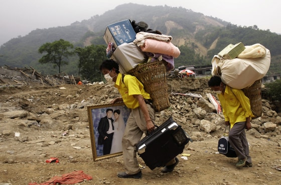 Two residents, one carrying a wedding picture of relatives and and other belongings, leave the disaster area in Beichuan county on Saturday. The man in the wedding image was killed in Monday's earthquake.