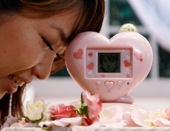 Bandai Co's employee Hirai poses with the company's latest electronic piggybank \"Ikemenbank\" at International Tokyo Toy Show in Tokyo