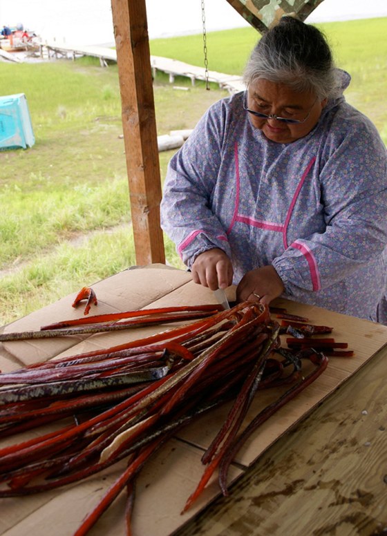 Aurie Waska uses an ulu knife to cut dried king salmon into strips at a fish camp on the lower Yukon River in Alaska. The fish is buoying the fragile economies of the tiny Yukon River delta villages, which are among the state's poorest communities.