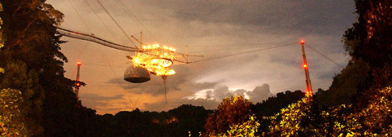 The Arecibo Observatory — the world's biggest single radio dish — glows amid a lightning storm at twilight.