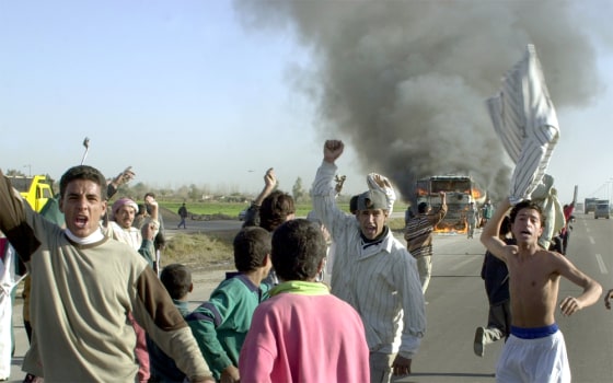 Iraqis celebrate near the wreckage of a burning tanker truck near Abu Ghraib, west of Baghdad, on Friday.