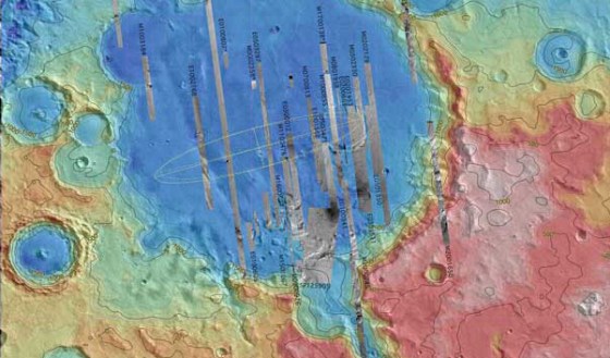 An image of Gusev Crater, the landing site for NASA's Spirit rover, is color-coded to show altitude. The projected landing area is indicated by the faint outline of an ellipse. A canyon called Ma'adim Valles is connected to the crater at the bottom of the image. Scientists believe Gusev Crater may have been an ancient lakebed.