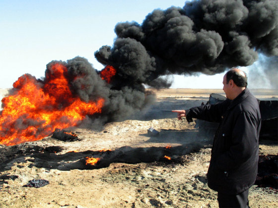 An Iraqi official of the Ministry of Oil looks at a burning pipeline last month near Samarra, 75 miles north of Baghdad. Thieves trying to steal gasoline caused an explosion when they breached a pipeline creating a blaze that burned out three cars that were loaded with barrels of gas. 