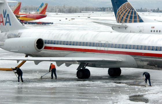 Workers try to clear ice under an American Airlines jet at Portland International Airport on Thursday. 