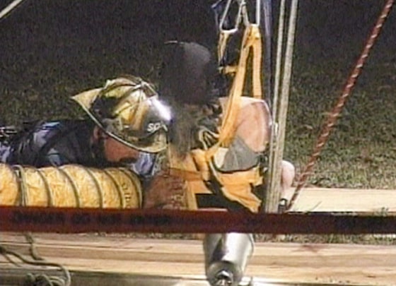 Rescue workers peer into the hole that Linda Sharp fell into while walking her dog, Bouncer.