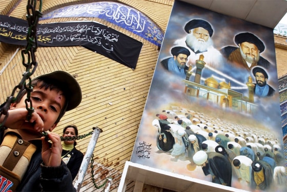 An Iraqi Shiite muslim boy and his mother exit the Kadimiyah shrine beneath a giant mural of important Iraqi Shiite clerics in Baghdad. 
