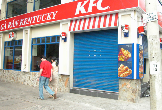 PEDESTRIANS WALK PAST A SHUTTERED KENTUCKY FRIED CHICKEN RESTAURANT IN HO CHI MINH CITY