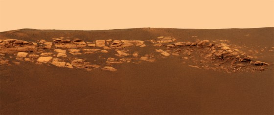 A color picture from the panoramic camera on the Opportunity rover shows bedrock outcroppings sticking up as much as a foot and half from darker material within the crater where the rover rests.