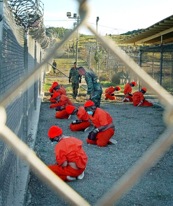 Muslim prisoners in orange jumpsuits sat in a holding area under the watchful eyes of military police at Camp X-Ray in January 2002. 