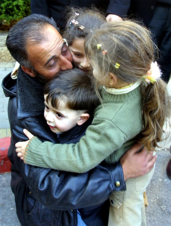 A RELEASED PALESTINIAN PRISONER HUGS HIS THREE CHILDREN AFTER HE WAS RELEASED IN THE WEST BANK
