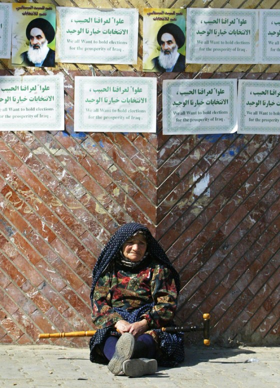 An elderly Iranian pilgrim leans against a wall plastered with posters calling for elections in Iraq and portraits of Shiite leader Grand Ayatollah Ali al-Husseini al-Sistani on Tuesday in Baghdad's Shiite neighborhood of Kazemiya. 