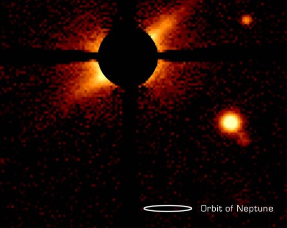 In this picture of the AU Microscopium star system, the central glare of the star itself has been blocked out. The dusty disk can be seen to the lower left and the upper right of the blocked-out area. A small white oval corresponding to the size of Neptune's orbit has been added to the bottom of this image for comparison's sake.