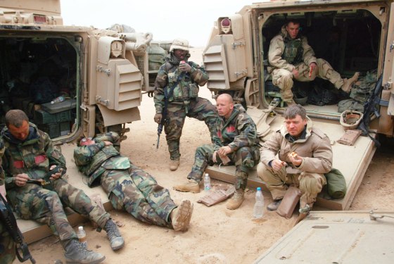 Chris Tomlinson, right front, a reporter for the Associated Press, eats a "meal ready to eat" at a temporary camp in the desert with U.S. Army soldiers about 100 miles south of Baghdad on March 24, 2003. Tomlinson was among journalists "embedded" with the troops during the war in Iraq.