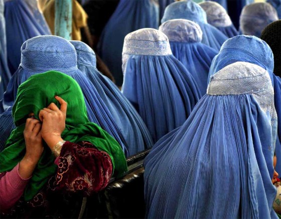 A young girl joins the crowd of burka-clad women by hiding her face at the site of a male visitor at a medical clinic in Karabagh.