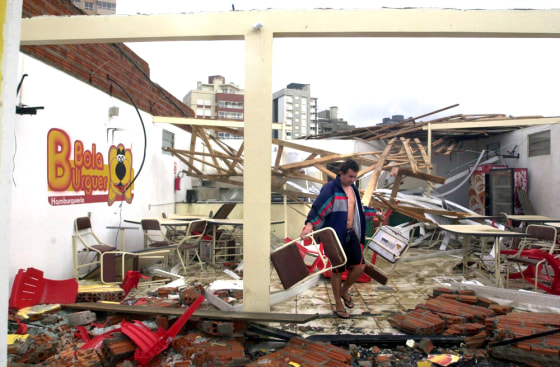 A man picks up furniture inside the remains of what used to be a snack bar in Torres, Brazil, Sunday, after a powerful storm lashed the nation's southern coast.