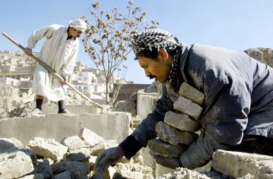 MEN PICK THROUGH RUBBLE