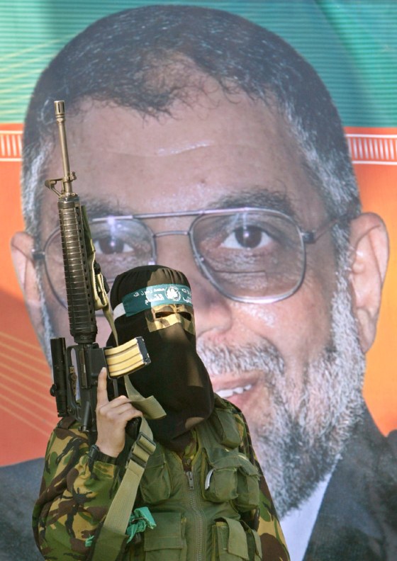 MASKED PALESTINIAN HAMAS MILITANT MARCHES IN FRONT POSTER OF SLAIN HAMAS LEADER ABDEL AZIZ AL-RANTISSI AT KHAN YOUNIS REFUGEE CAMP