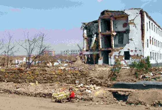 NORTH KOREAN WOMAN SITS IN FRONT OF RUINED BUILDING AFTER EXPLOSION IN RYONGCHON