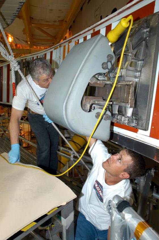 Technicians Jake Jacobson and Billy Barecka install a reinforced carbon-carbon panel on the right wing of the space shuttle Discovery at NASA's Kennedy Space Center. Discovery is due to take the first shuttle flight since last year's Columbia tragedy.